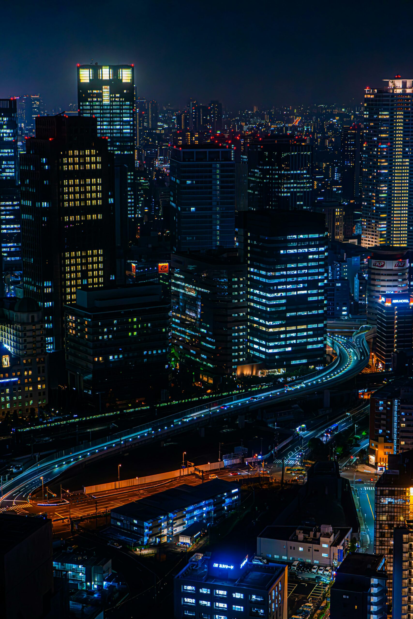 A stunning aerial view of a bustling urban skyline at night with glowing skyscrapers and city lights.